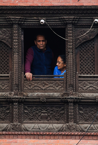 Kathmandu. Nepal - March 30, 2016: Nepalian seniors couplel in traditional asian dress  looking out the windowl 