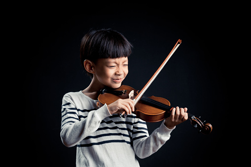 boy playing a Violin isolated over a black background