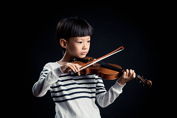 istock boy playing a Violin isolated over a black background 619535490