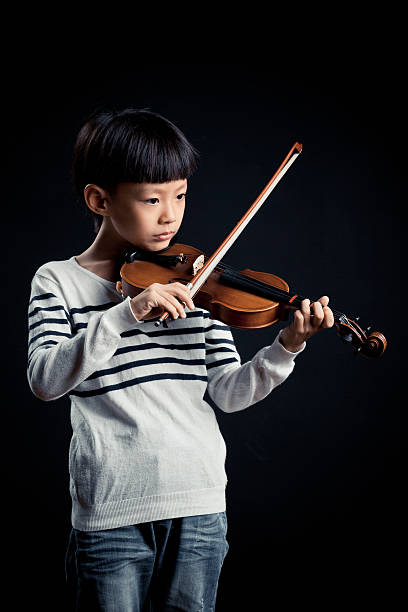istock boy playing a Violin isolated over a black background 619536150