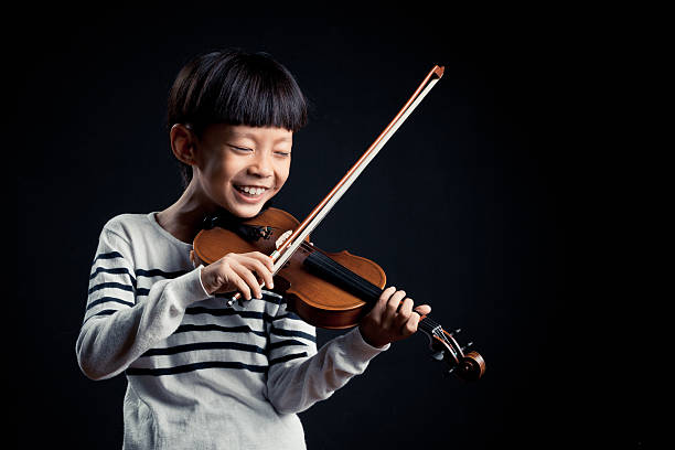 istock boy playing a Violin isolated over a black background 619536370