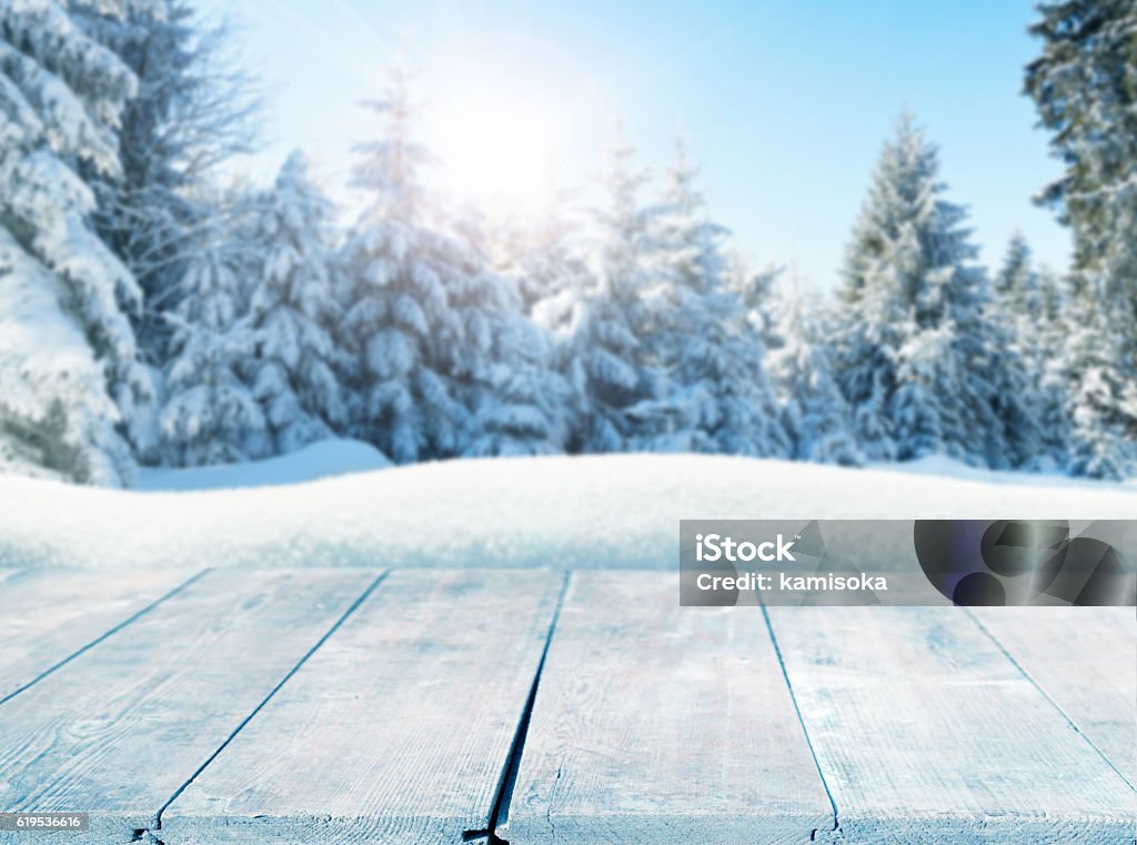 Winter background with snow-covered pine trees behind empty wooden planks Table Stock Photo