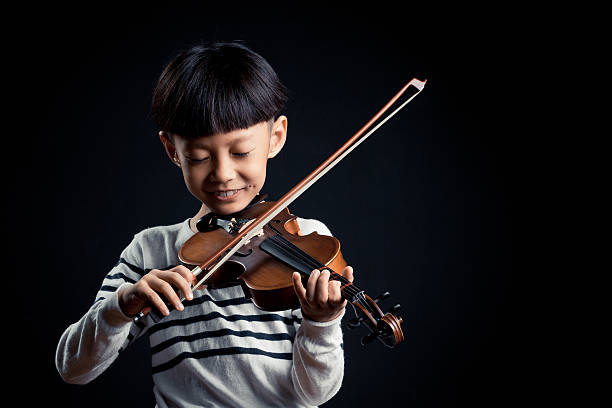 istock boy playing a Violin isolated over a black background 619536740