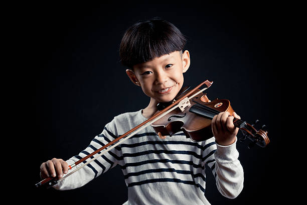 istock boy playing a Violin isolated over a black background 619537340