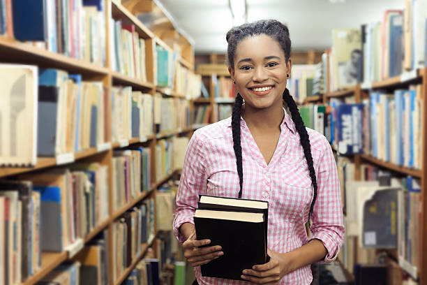 istock Smiling female student holding books at the library 619537956