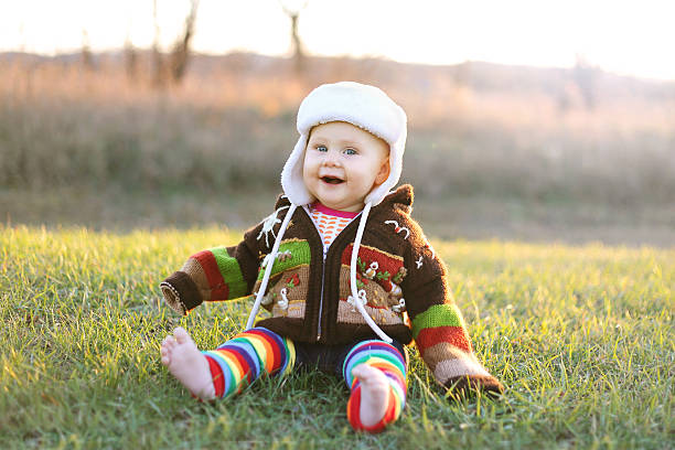 entzückende baby mädchen in winterhut und pullover lachen draußen - beinwärmer stock-fotos und bilder