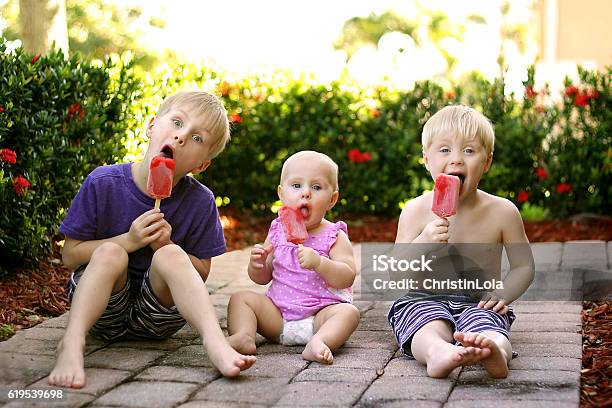 Three Children Eating Fruit Popsicles Outside On Summer Day Stock Photo - Download Image Now