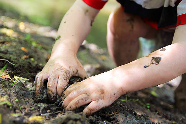 Little Child's Hands Digging in the Mud The Dirty hands of a little boy child are digging in the wet mud outside by the river. dirty hands stock pictures, royalty-free photos & images