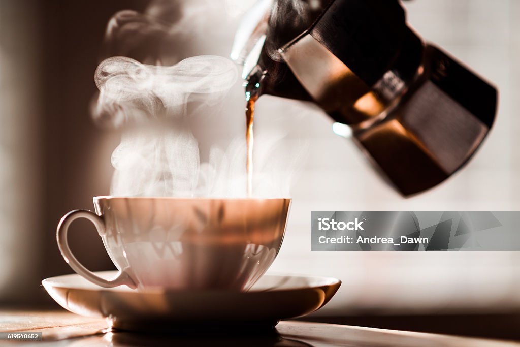 Morning Coffee Pour in Coffee Cup Espresso Maker with Steam Coffee being poured into a coffee cup from Espresso Maker with beautiful steam in the morning light. Coffee - Drink Stock Photo