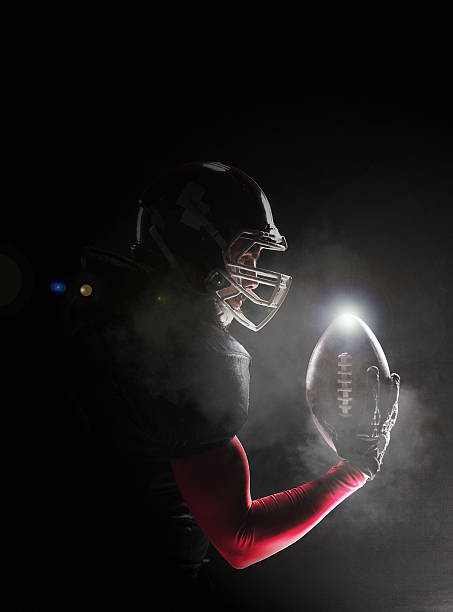 American football player posing with ball on black background Caucasian fitness man as american football player holding a ball on black background american football ball photos stock pictures, royalty-free photos & images