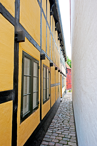 Aalborg,Denmark - June 22, 2016: Narrow cobbled alleyway reveals this restored and preserved half-timbered and painted house facade in Aalborg old city centre, dating from the Middle Ages. Many of the old half timbered properties, for the most part, were torn down to make way for industrialisation in the early 20th century but this example demonstrates how close properties were to one another.