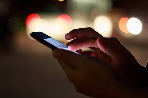 mano de cerca usando el teléfono en la noche en la calle - marcar usar el teléfono fotografías e imágenes de stock