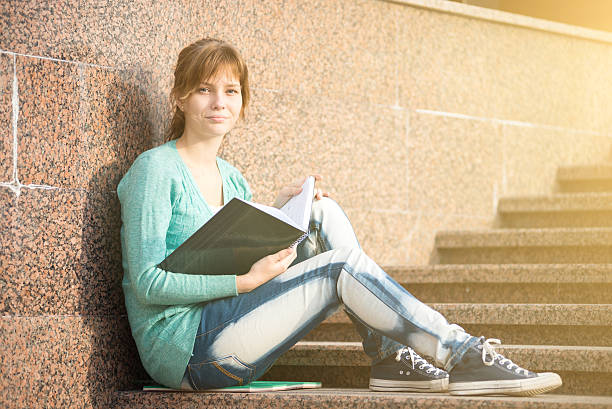 istock Girl sitting on stairs and reading note 619544210