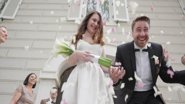 SLO MO Newlyweds being showered with roses when leaving church