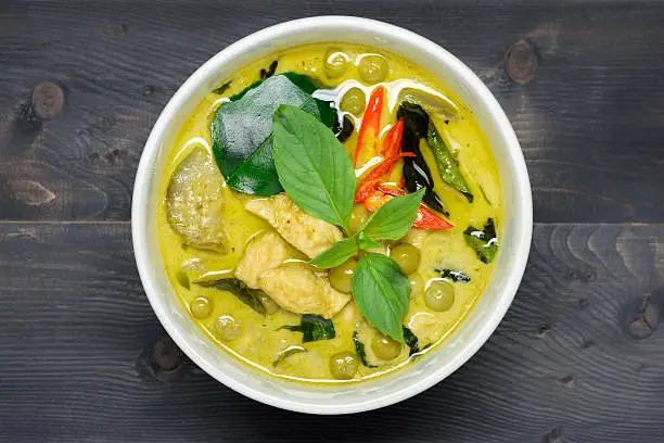 green curry with chicken (Kang Keaw Wan Gai) on wooden background top view, Thai local food