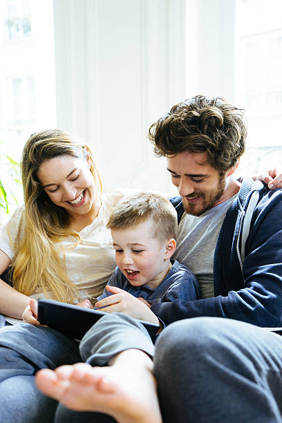 istock Cheerful Young Family Looking At Digital Tablet Together 619628436