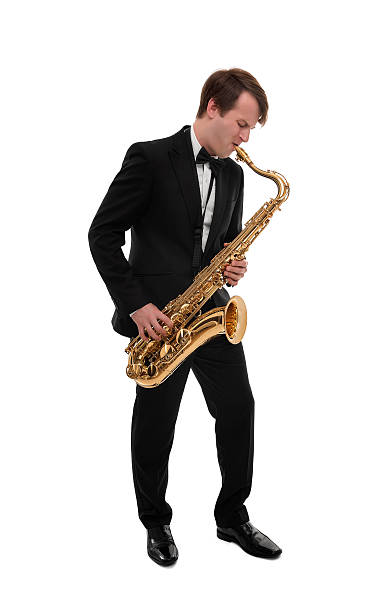 Beautiful schoolboy in hooded sweatshirt playing saxophone in neon lit room in the evening