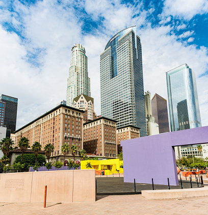 Los Angeles, USA - October 29, 2016: Detail of Pershing Square in central Los Angeles. A public park with coloured blocks. Skyscrapers in the background with Deloitte, Citi logos, A man sits on a wall in the distance.