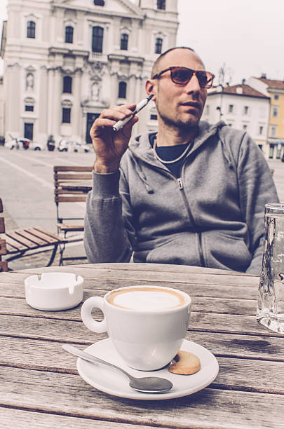 istock Man using electronic cigarette and drinking coffee, bar in Italy 619635338