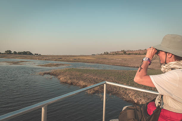 istock Tourist watching wildlife by binocular on Chobe River 619635664