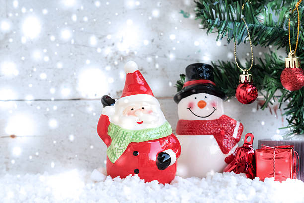 istock Santa Claus with snowman and snowfall over fir tree 619637486