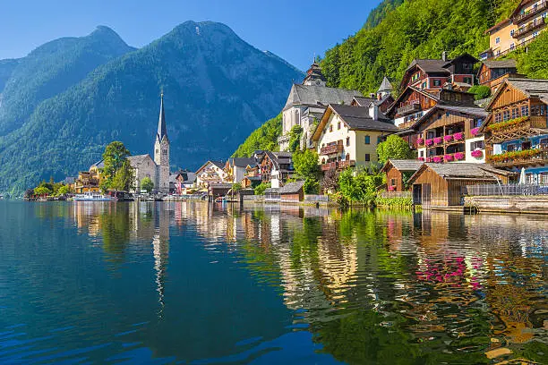 Scenic picture-postcard view of famous Hallstatt village reflecting in Hallstattersee lake in the Austrian Alps in beautiful morning light on a sunny day in summer, Salzkammergut region, Austria.