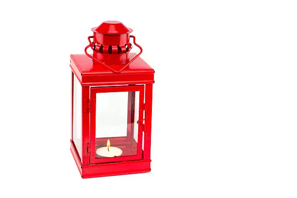 Red metal lantern with burning tealight isolated on white background. The object is used for decoration indoors.