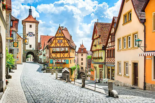 Beautiful postcard view of the famous historic town of Rothenburg ob der Tauber on a sunny day with blue sky and clouds in summer, Franconia, Bavaria, Germany.