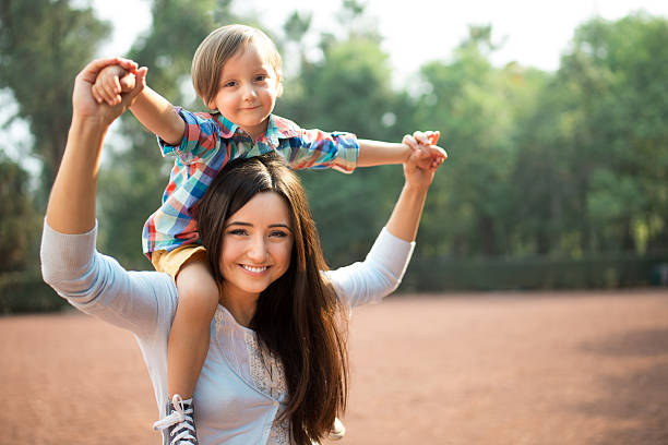istock Young mother carrying son on shoulders and holding hands 619642462