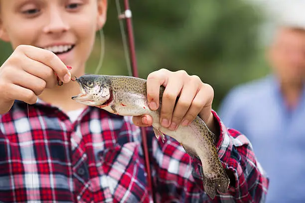 Photo of Teenager boy looking at fish on hook