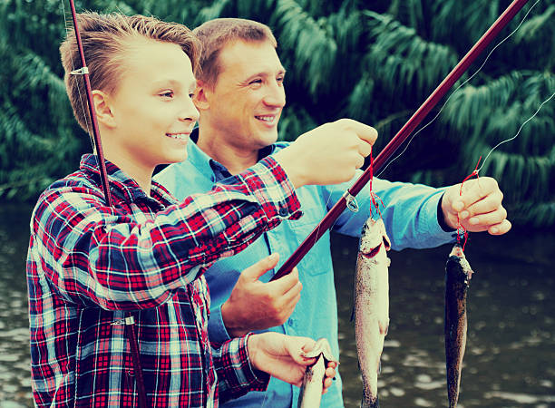 istock Man with teenager boy showing catch fish 619645390