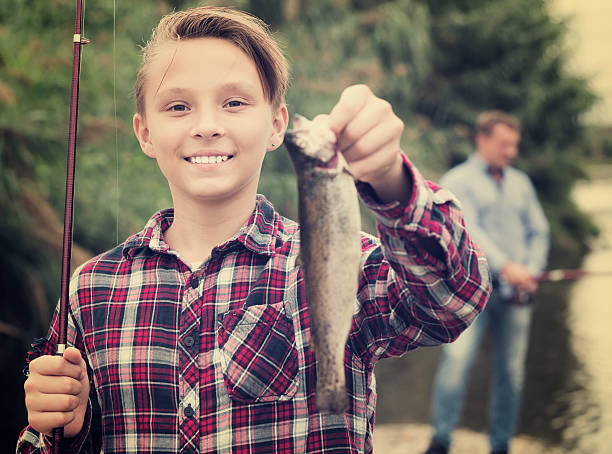 istock Boy holding catch freshwater fish in hands 619646770