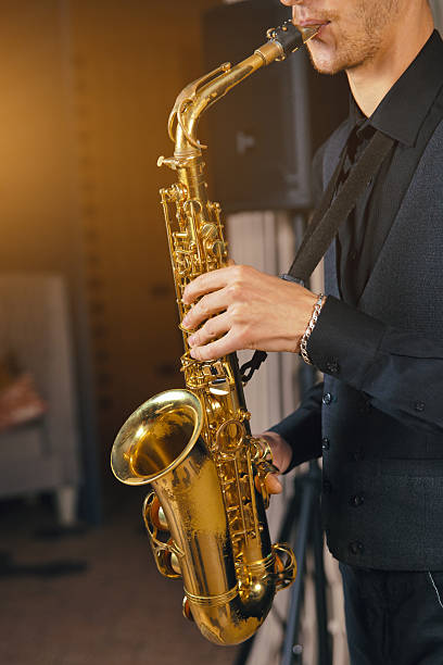 istock Young man in a suit hold saxophone 619647570