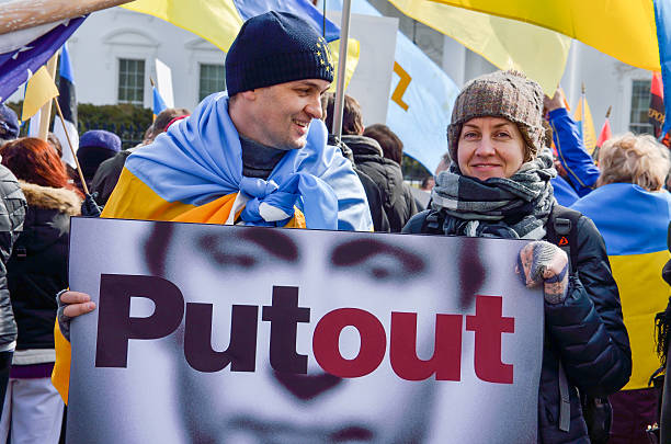 Man and woman holding Vladimir Putin sign during Ukrainian protest Washington DC, USA - March 6, 2014: Man and woman holding Vladimir Putin sign stating Putout during Ukrainian protest with flags by White House golden ring of russia photos stock pictures, royalty-free photos & images