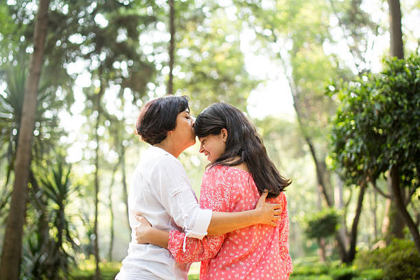 mère latine embrassant sa fille sur le front - back to front photos et images de collection