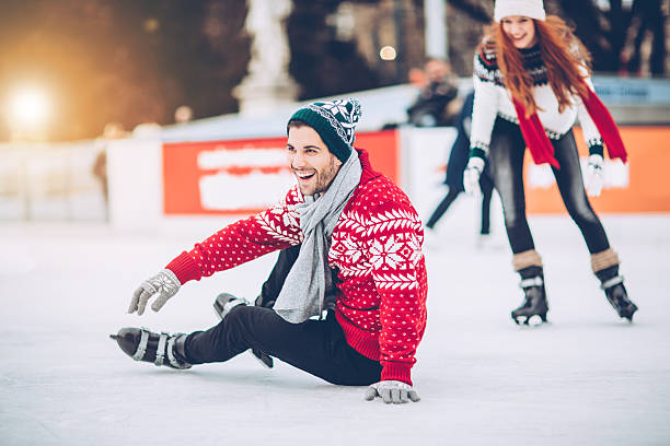 I'm still learning how to skating on ice Friends having so much fun while ice skating. Wearing warm clothing. City is decorated with christmas lights. ice rink stock pictures, royalty-free photos & images
