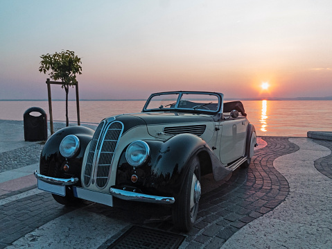 The old car on the Garda Lake at sunset