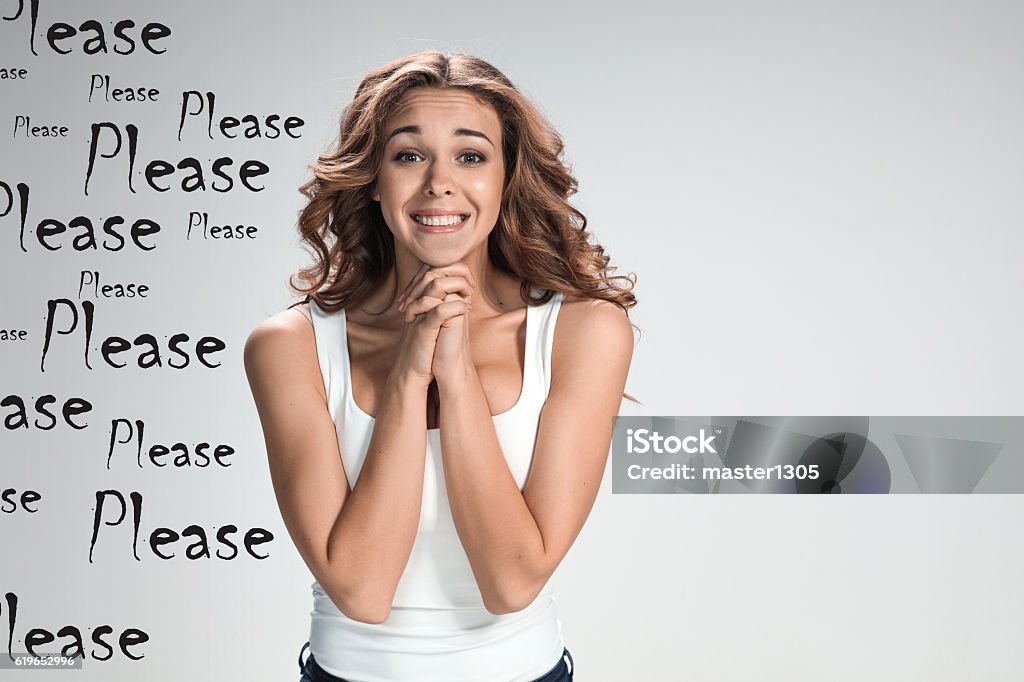 The young woman's portrait with happy emotions The young appealing womant with happy emotions on gray background with mark PLEASE Pleading Stock Photo