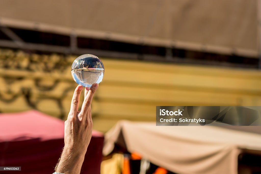 Hand holding a crystal ball Hand of a young magician playing with a crystal ball during a medieval market. Astronomy Stock Photo