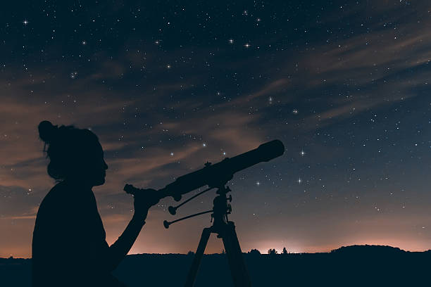 woman with astronomical telescope. night sky, with clouds and constellations - astronomia imagens e fotografias de stock