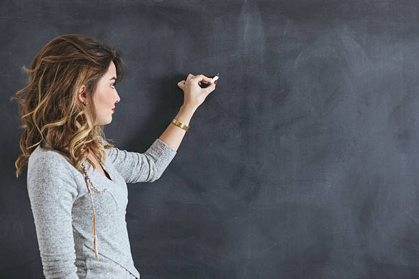 jovem professor escrevendo em um quadro-negro - blackboard writing chalk teacher - fotografias e filmes do acervo