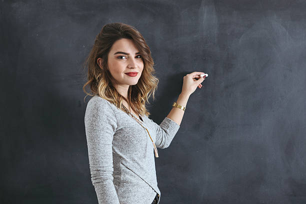 istock Young teacher writing on a blackboard 619657450