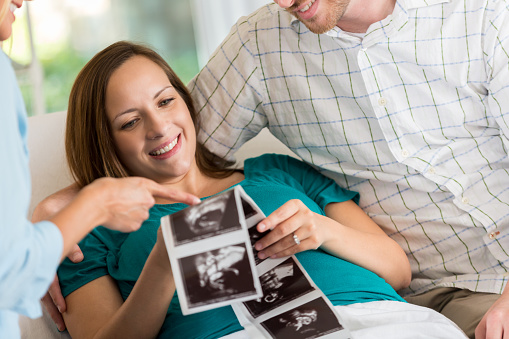 Happy expectant mother and father are excited while they looks at sonogram images of their baby.