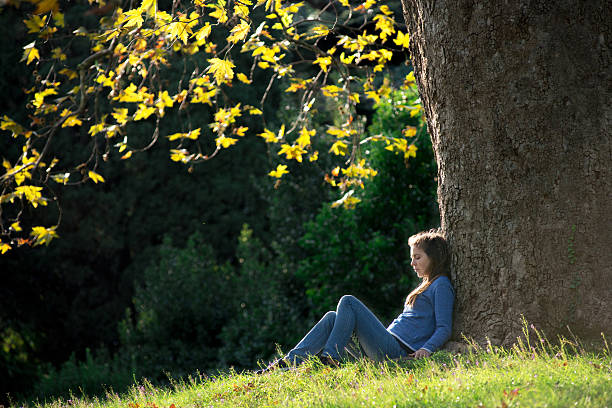 istock Girl sitting on the grass under maple tree in autumn 619660952