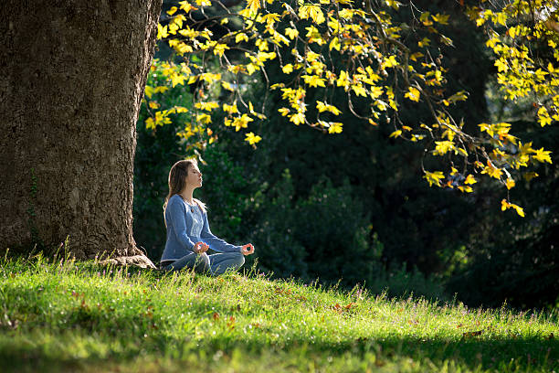 istock Girl meditates on the grass under maple tree in autumn 619661588