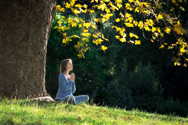 istock Girl meditates on the grass under maple tree in autumn 619661996