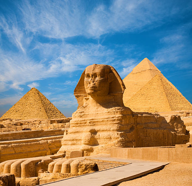 Sphinx Full Body Blue Sky All Pyramids Egypt Egyptian Great Sphinx full body portrait with head, feet with all pyramids of Menkaure, Khafre, Khufu  in background on a clear, blue sky day in Giza, Egypt empty with nobody. copy space giza stock pictures, royalty-free photos & images