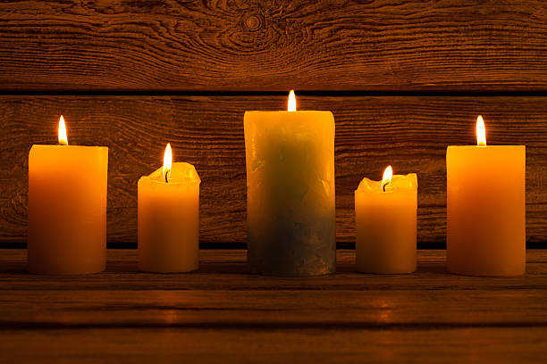 istock Candles of different sizes on the wooden background. 619676098