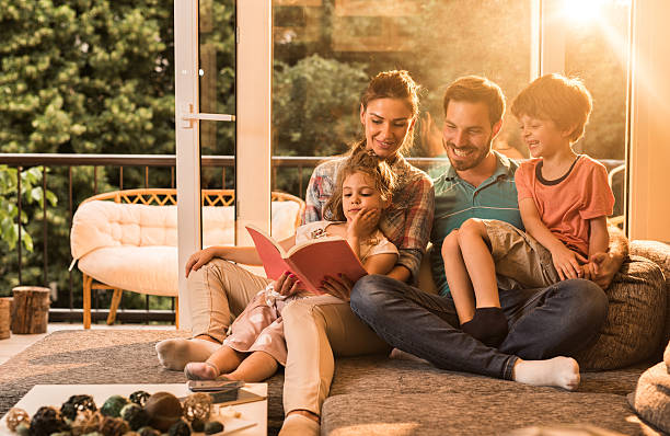 istock Happy parents reading a book with their small kids. 619727884