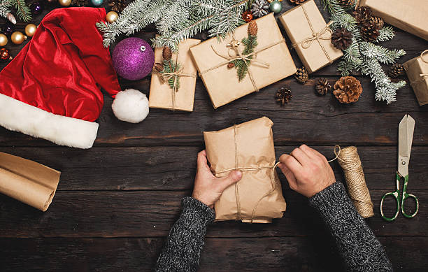 istock Man wraps Christmas gift on wooden table 619731822